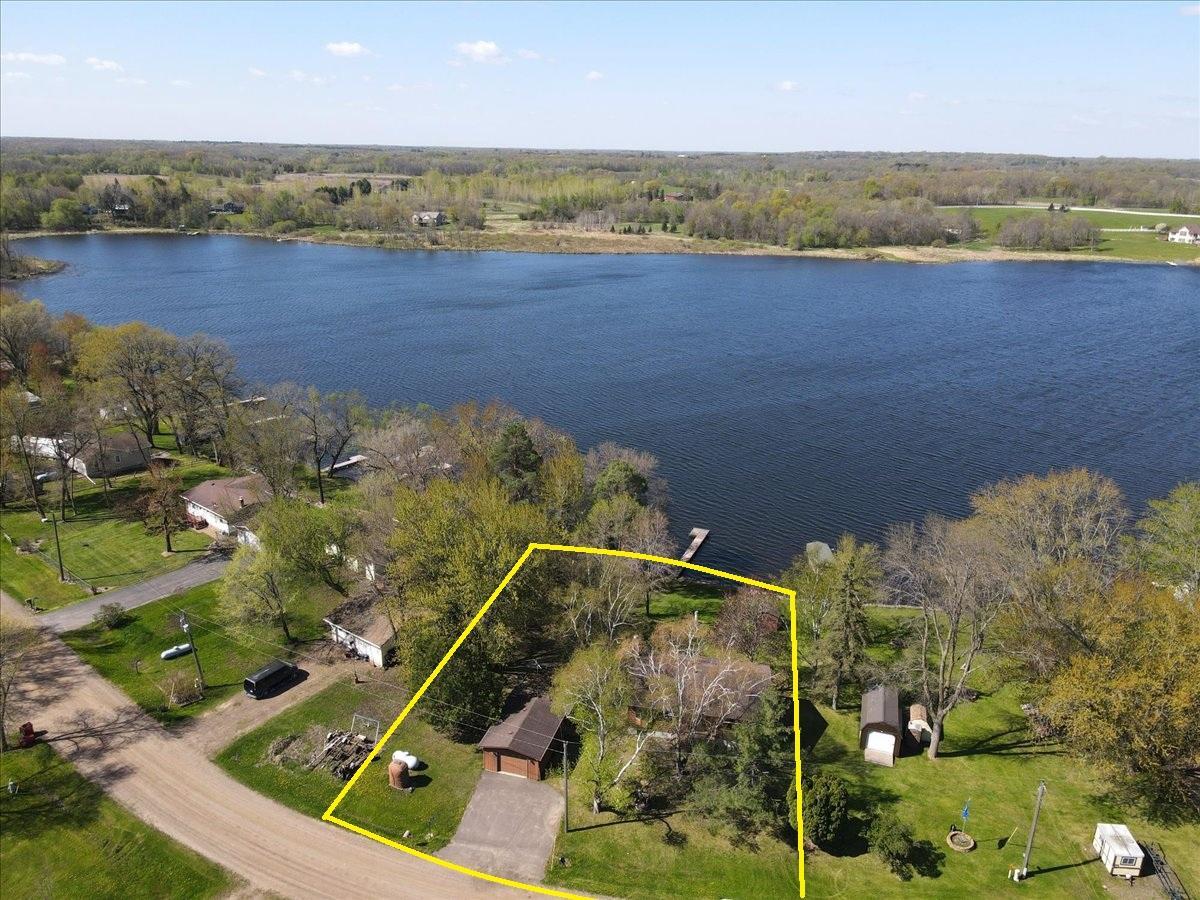 Approximate lot lines highlighting the home, detached garage, spacious yard, and lakefront setting.