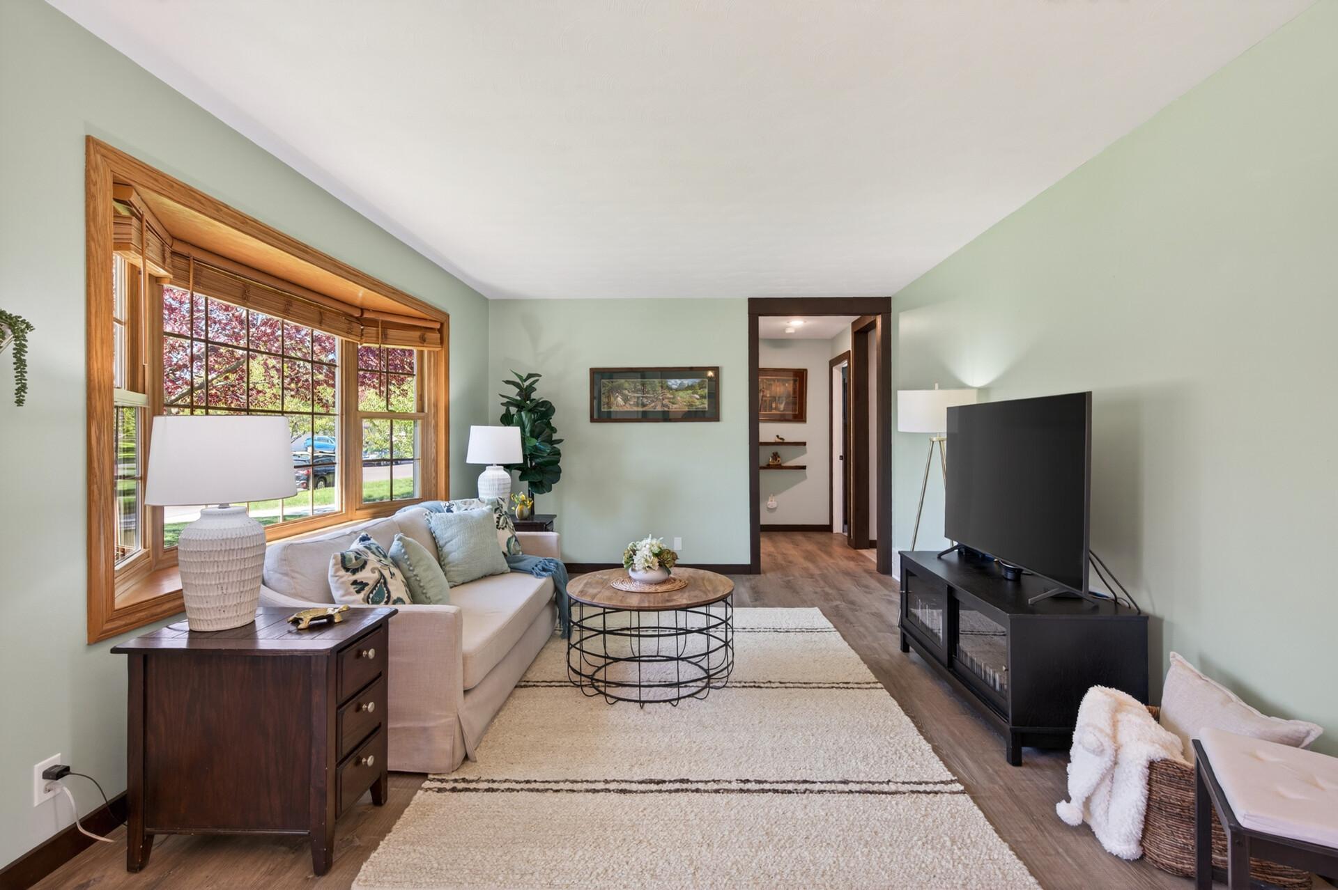 Bright living room features new flooring and a bowed window
