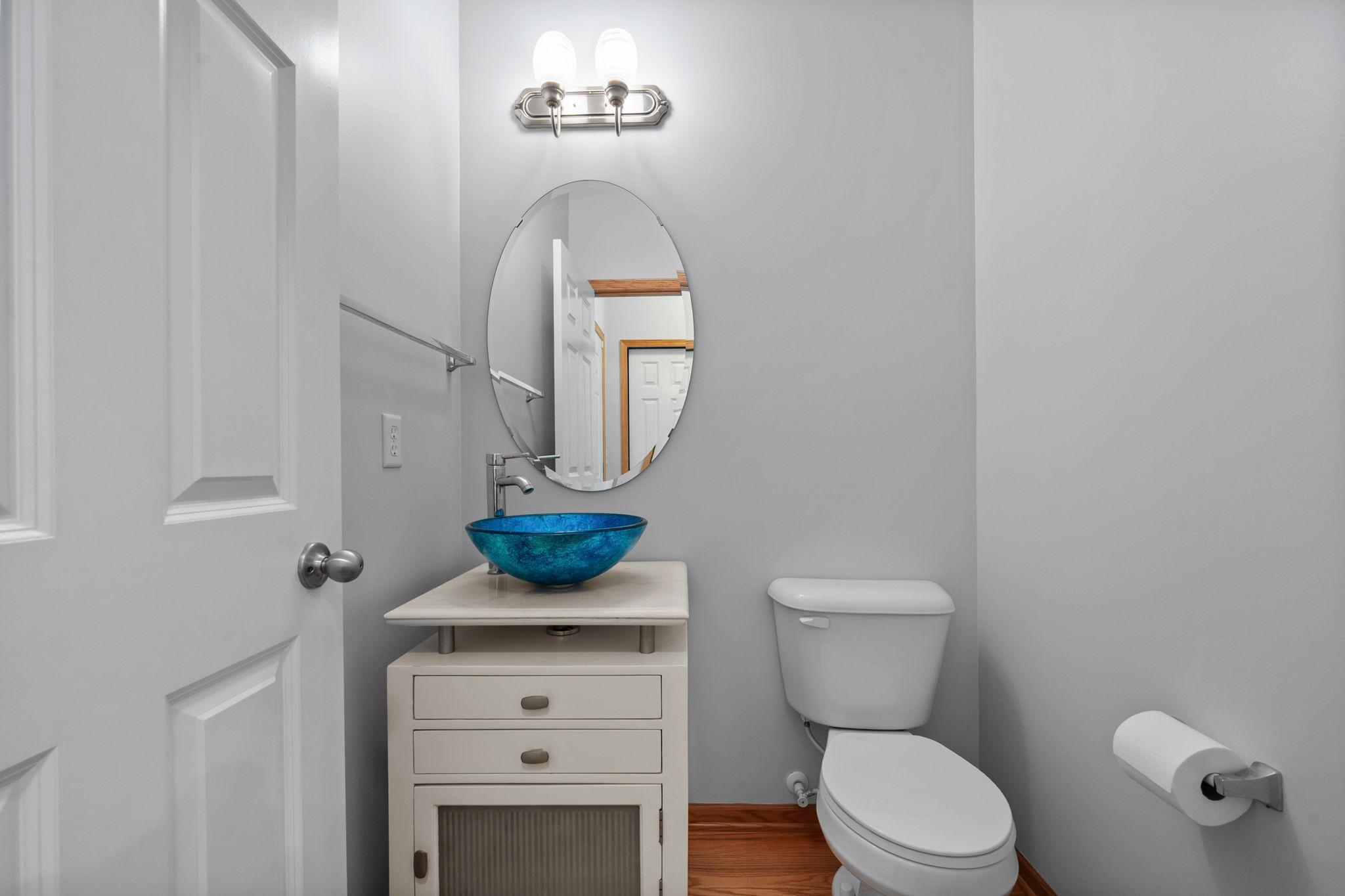 A stylish half-bath on the main level features a unique blue glass vessel sink and modern vanity.