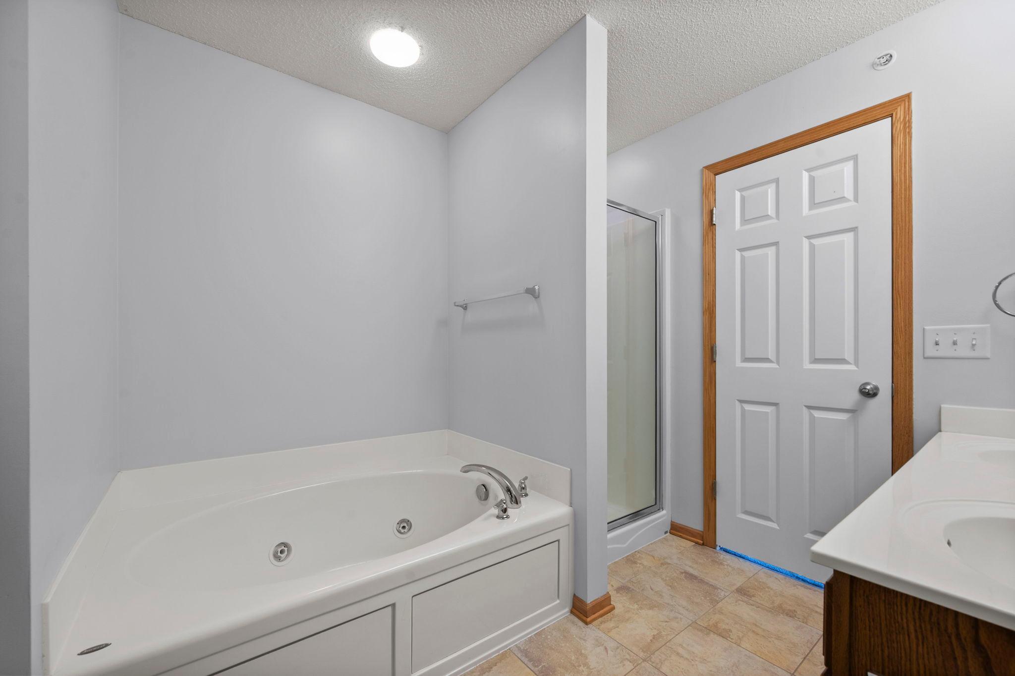 Relax in the primary suite's jetted soaking tub, complemented by a separate walk-in shower.