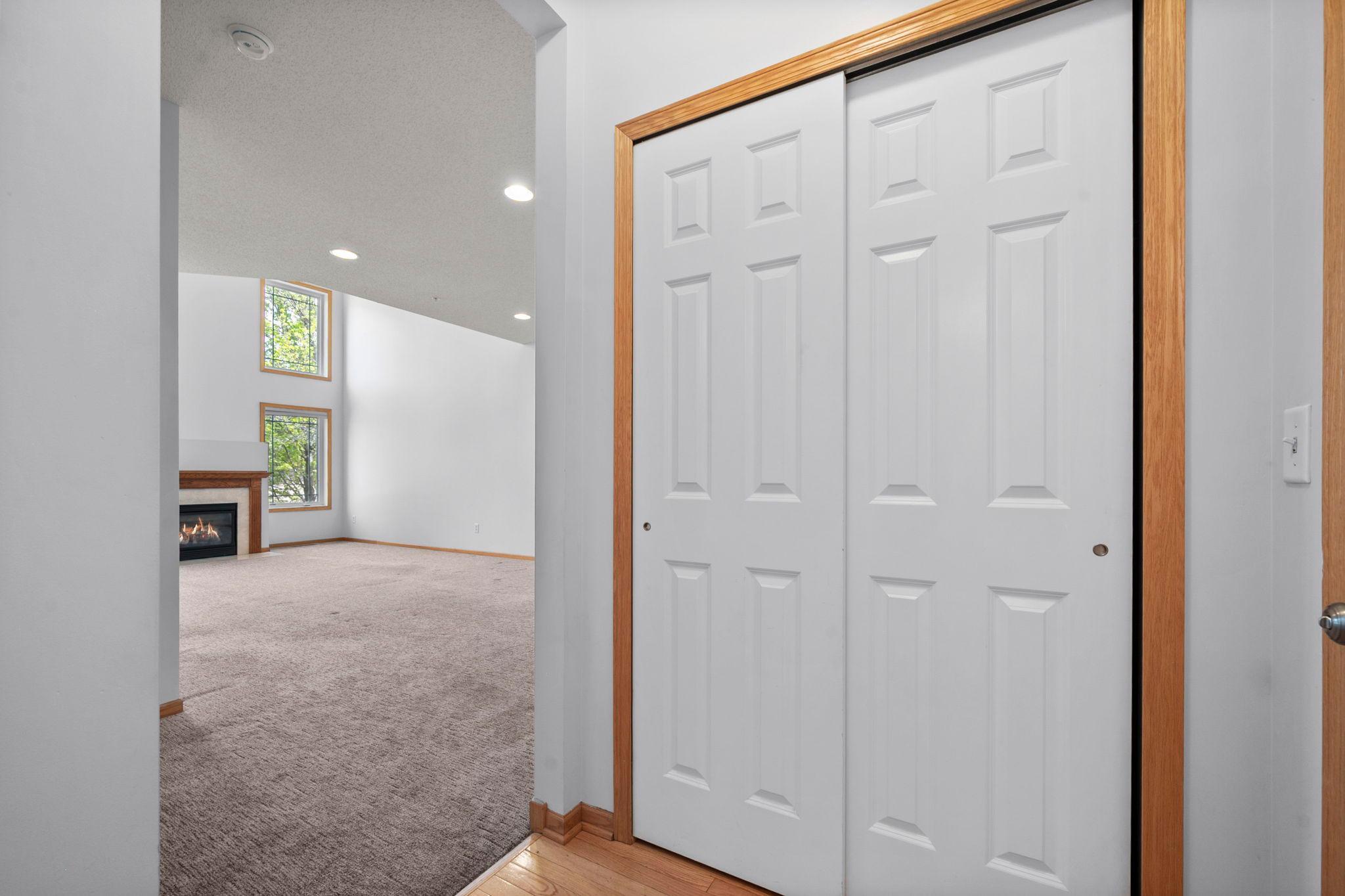 This hallway view shows a large storage closet and the transition into the light-filled main living room.