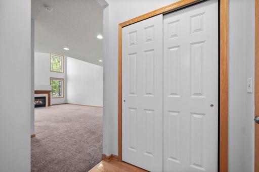 This hallway view shows a large storage closet and the transition into the light-filled main living room.