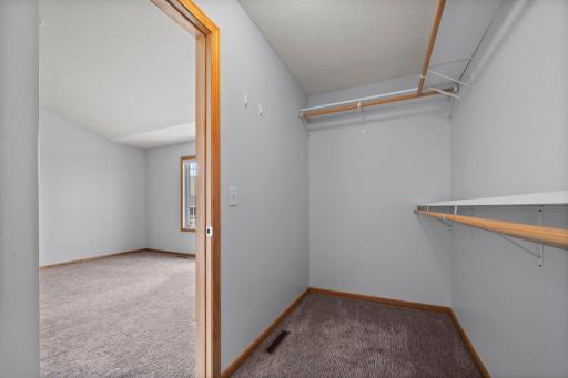 This primary closet features dual-level hanging space and integrated shelving to maximize organization.