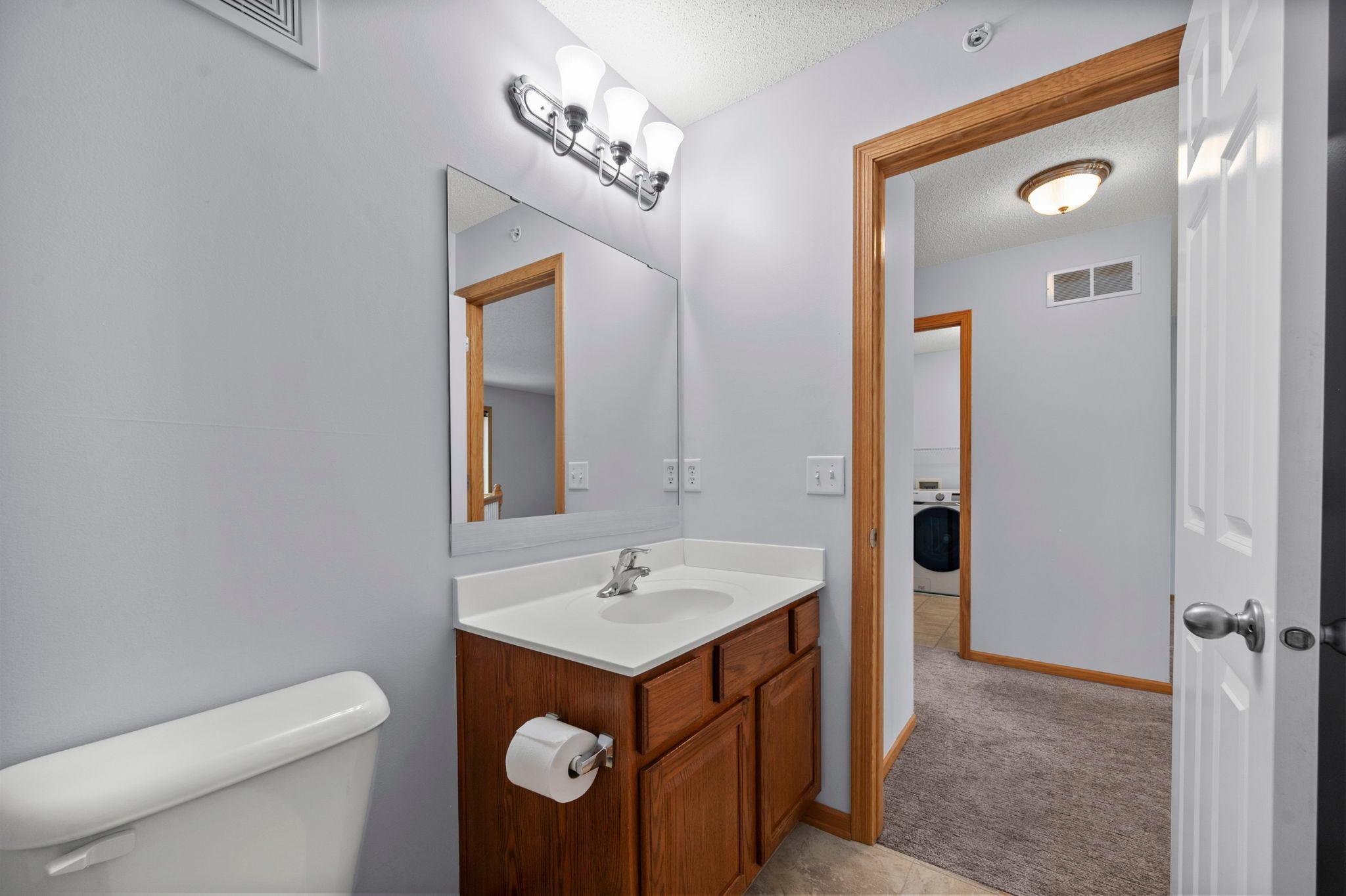 Well-maintained upper-level bathroom with ample lighting and a large vanity mirror.