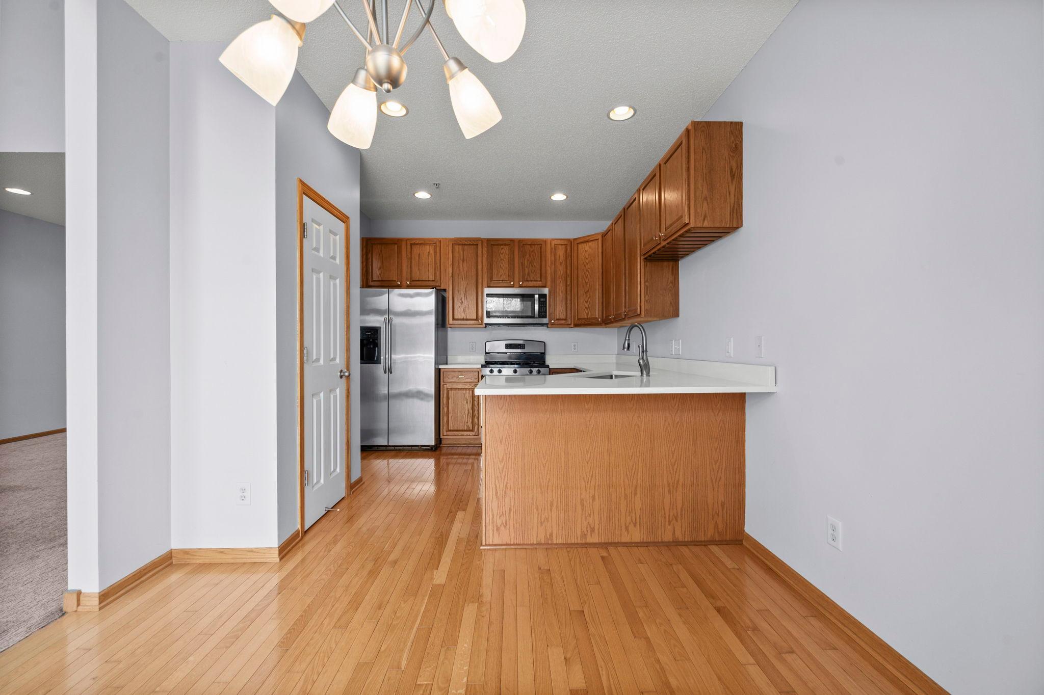 The functional kitchen features warm oak cabinetry, stainless steel appliances, and a convenient breakfast bar for casual dining.