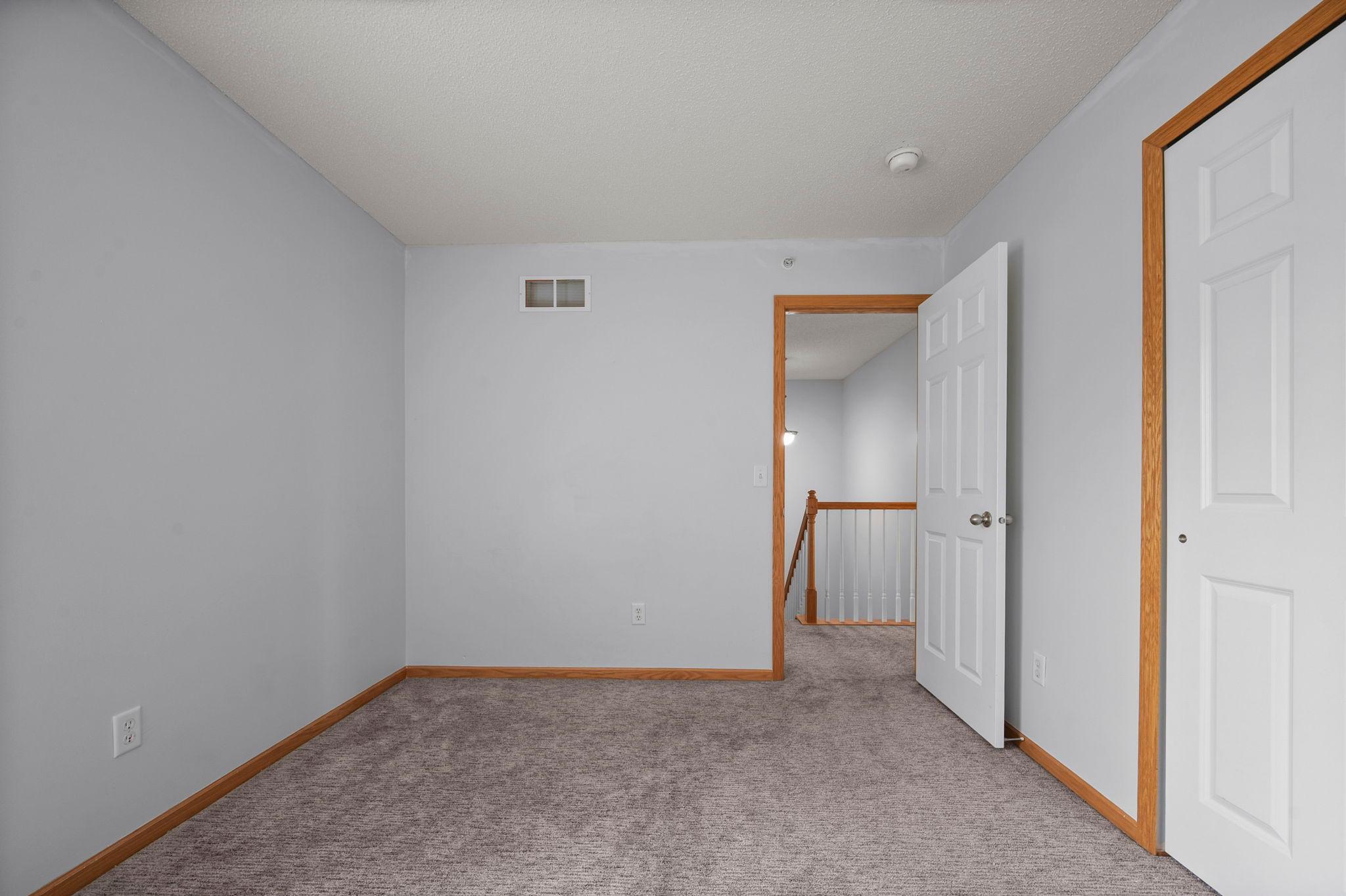 Another perspective of the third bedroom showing the view out toward the upper-level landing.