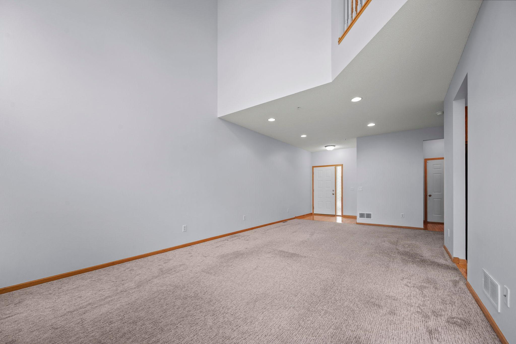 View from the main living area toward the entry foyer, highlighting the soaring ceilings and neutral color palette
