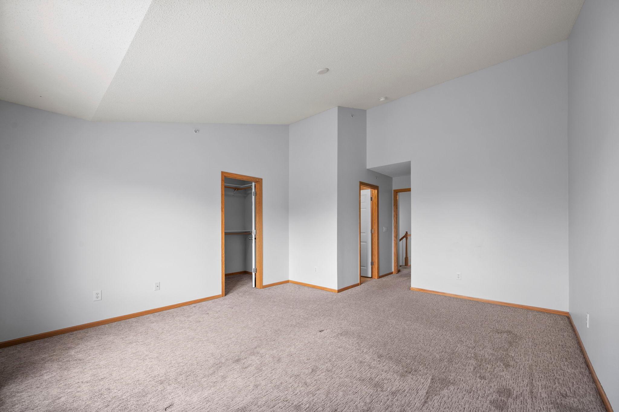 This bedroom view highlights the private nature of the upper level, complete with ample closet space and vaulted architectural details.