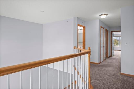 The upper hallway is well-lit and features classic wood railings that complement the home's neutral interior.
