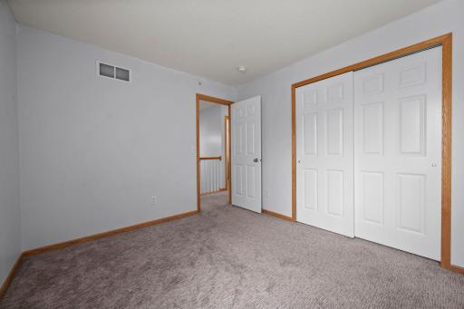 This bright third bedroom includes neutral carpeting, fresh paint, and a large closet with double sliding doors.