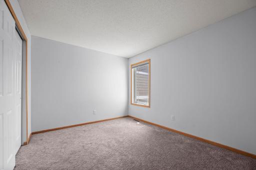 This secondary bedroom includes a large window and a spacious closet with sliding white doors.