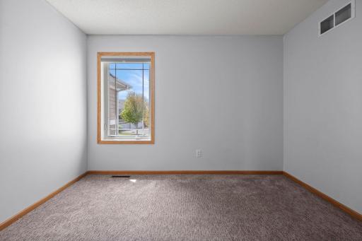 A bright and clean secondary bedroom, perfect for guests or family, featuring neutral paint and plush carpeting.