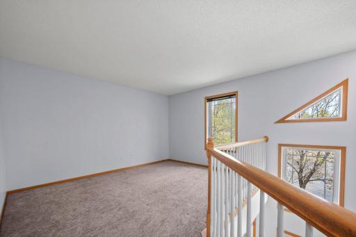 This versatile loft area features neutral carpeting and unique architectural window accents that overlook the main level.