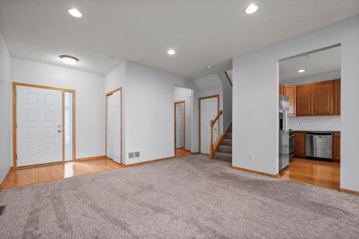 Inviting foyer with beautiful hardwood flooring, a convenient coat closet, and neutral carpeting.
Open-concept entryway showing the seamless flow from the front door into the main living areas and kitchen.
