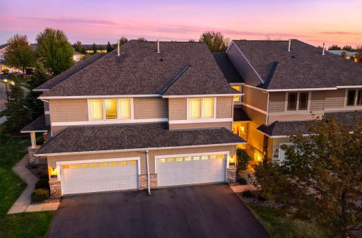 Stunning twilight view of this modern home featuring warm interior lighting and a spacious two-car garage.