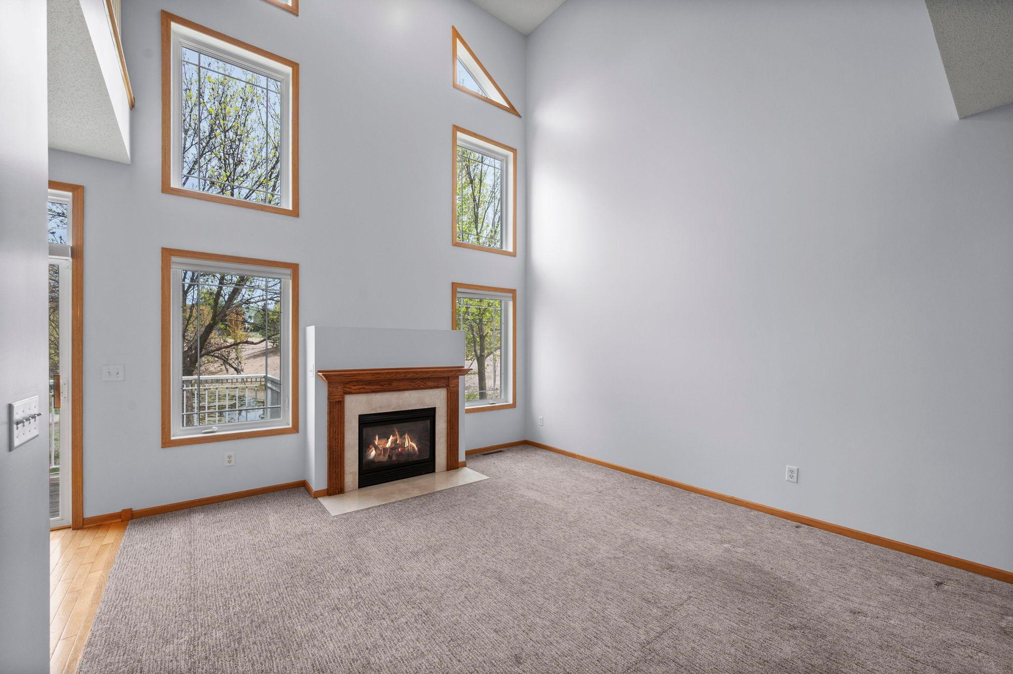 Bright and airy living space featuring a warm fireplace and large windows with serene views of the outdoors.