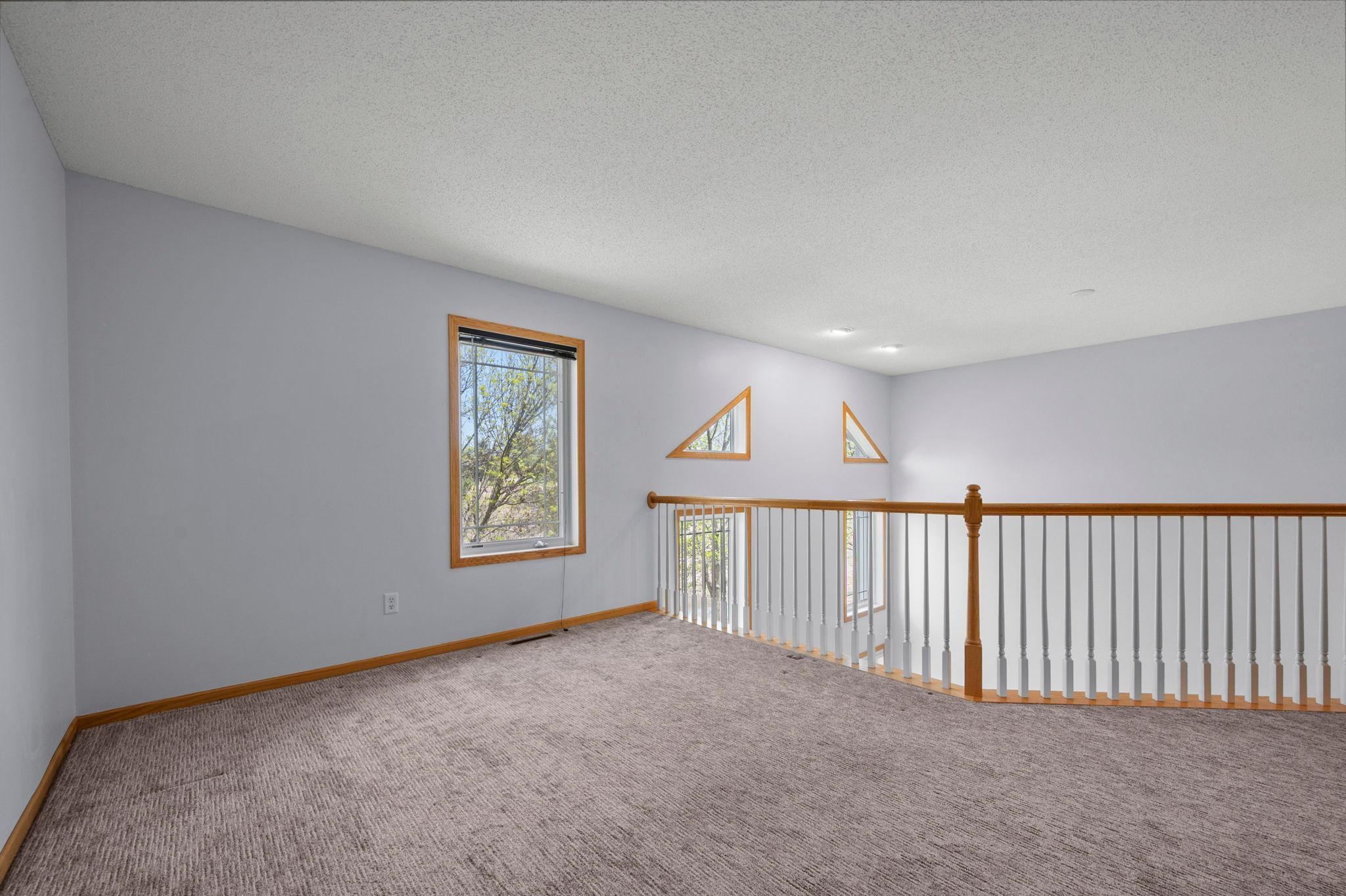 The loft's elevated position and large windows ensure the upper level feels airy and integrated with the home's open floor plan.
