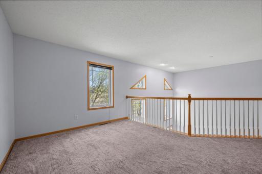 The loft's elevated position and large windows ensure the upper level feels airy and integrated with the home's open floor plan.