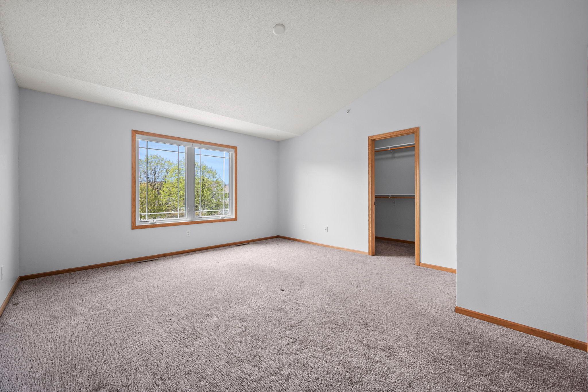 Another angle of the primary suite showcases the generous floor plan and the entrance to a walk-in closet.
