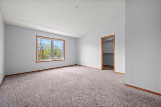 Another angle of the primary suite showcases the generous floor plan and the entrance to a walk-in closet.