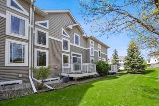 View of the rear exterior showing the home's multi-level design and the private wood deck overlooking the community lawn.