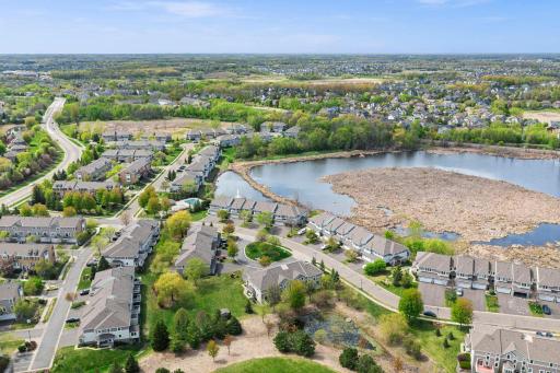Panoramic aerial shot showcasing the home's stunning proximity to the neighborhood pond and winding walking trails.