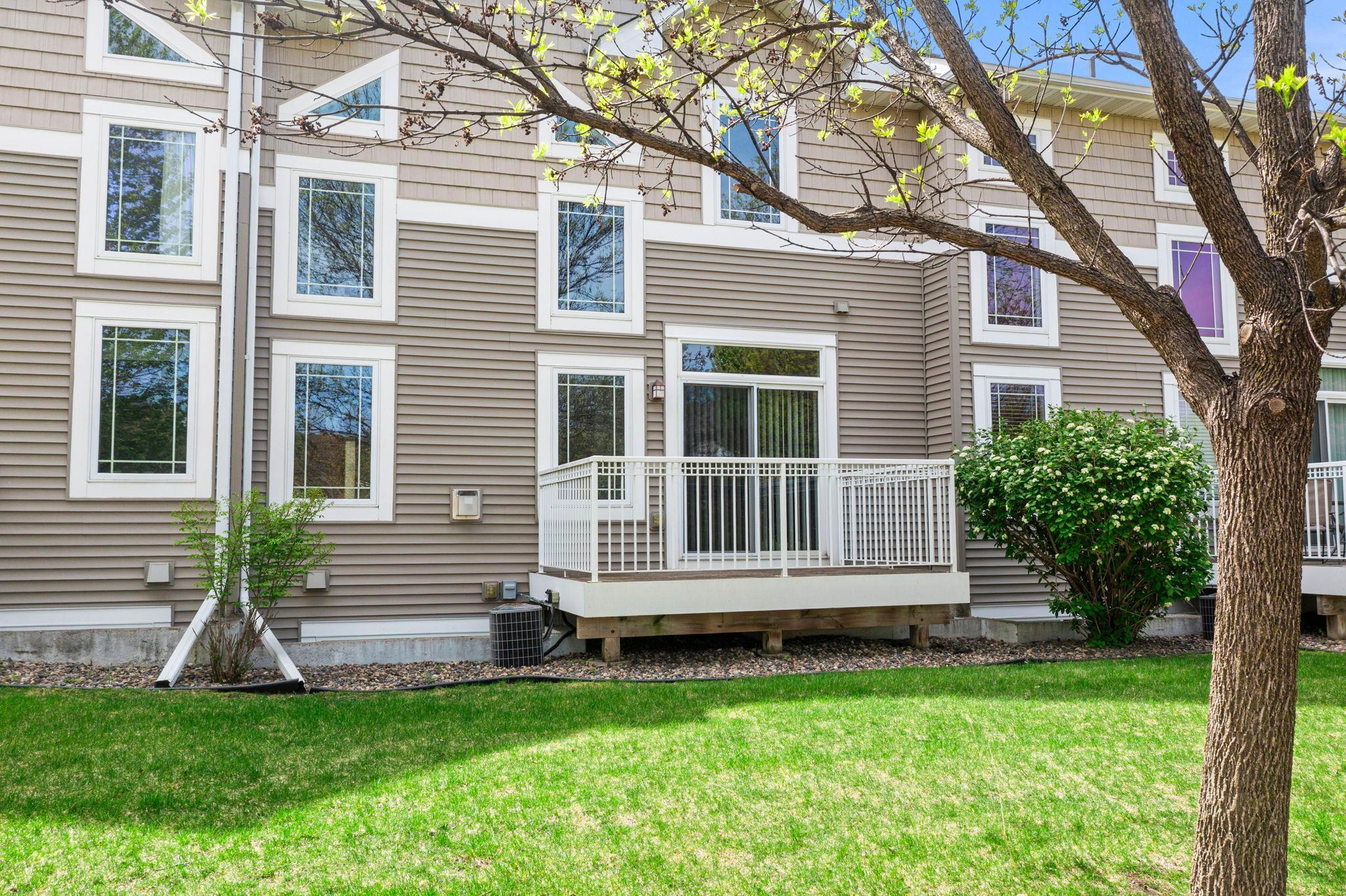 Direct rear view of the unit and deck, framed by blooming landscaping for a peaceful outdoor retreat.