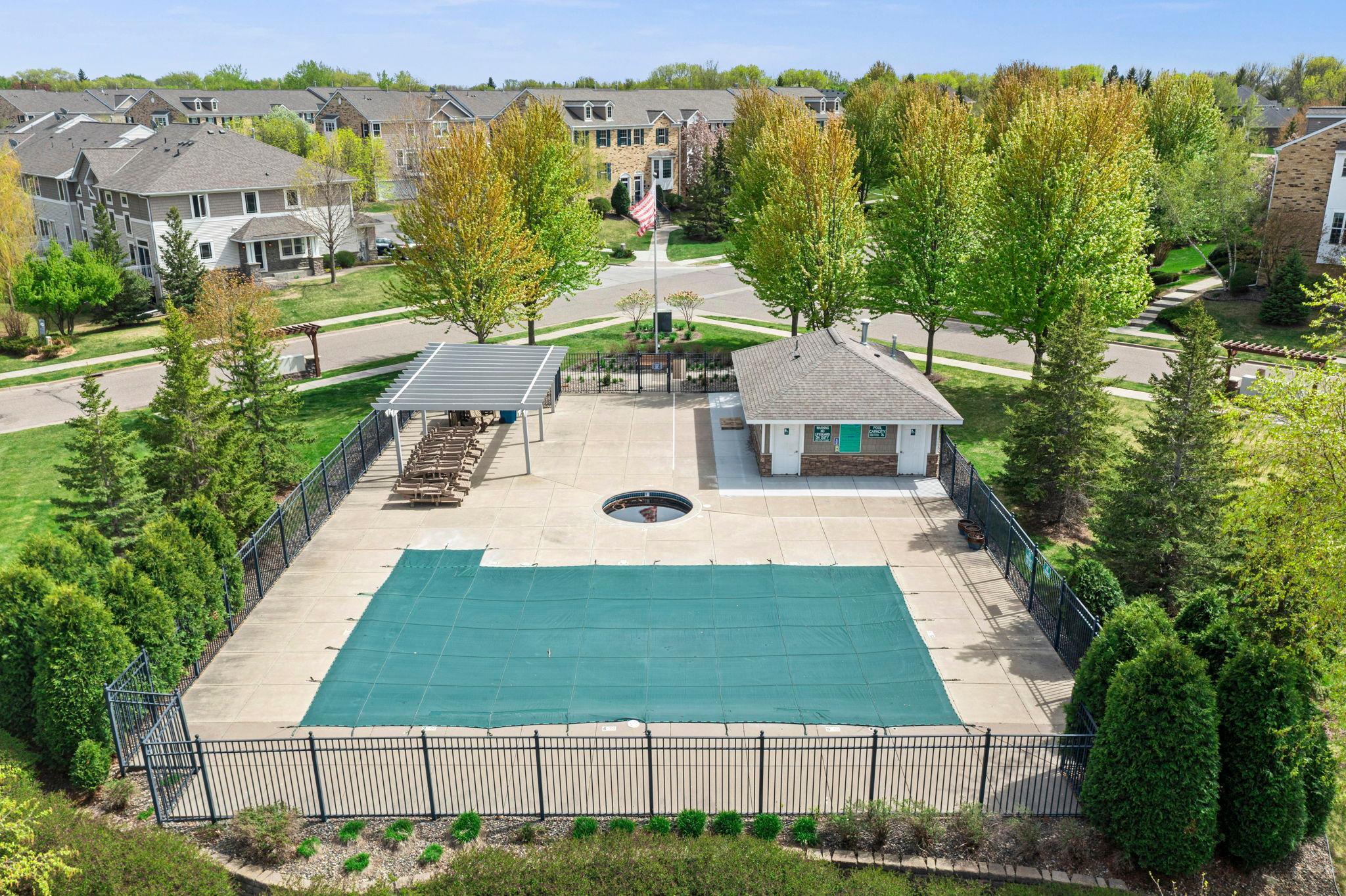The fenced-in pool area features a large sun deck, a shaded pergola, and a convenient pool house with changing facilities.