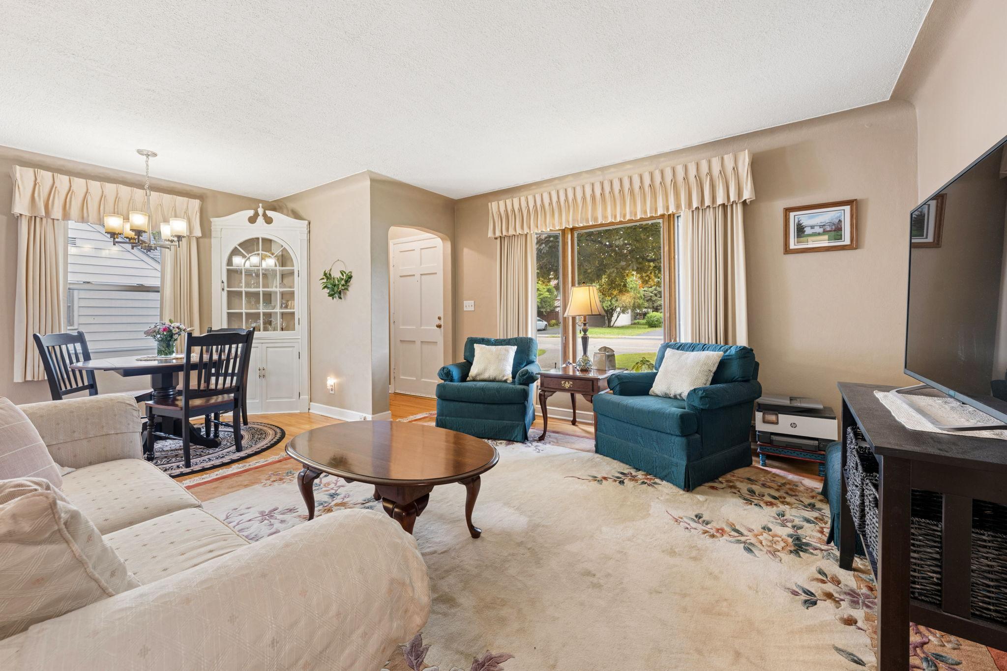 Spacious formal living room with large bay window and adjacent dining area.