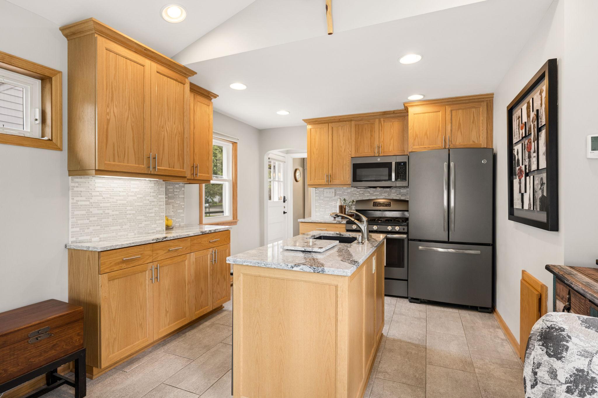 Updated kitchen with quartz countertops, matte stainless steel appliances, tile backsplash, light oak cabinetry and contemporary pulls.