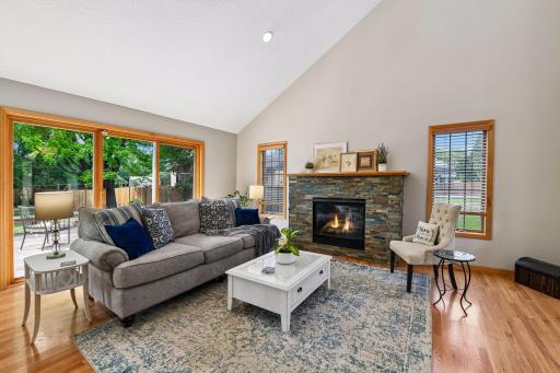 Relax in a light filled living room with beautiful hardwood floors, large windows and cozy, gas fireplace