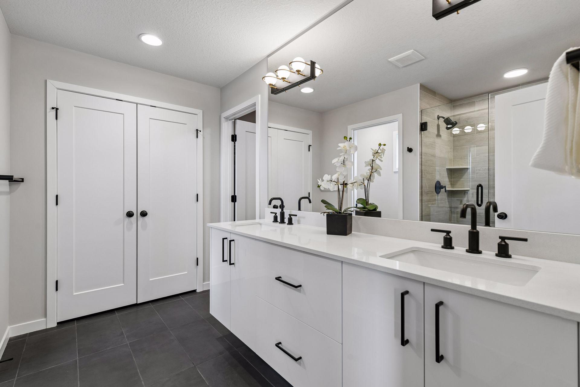 Luxury primary bath with dual-sink vanity, sleek black fixtures, generous storage, and a beautifully finished walk-in shower.