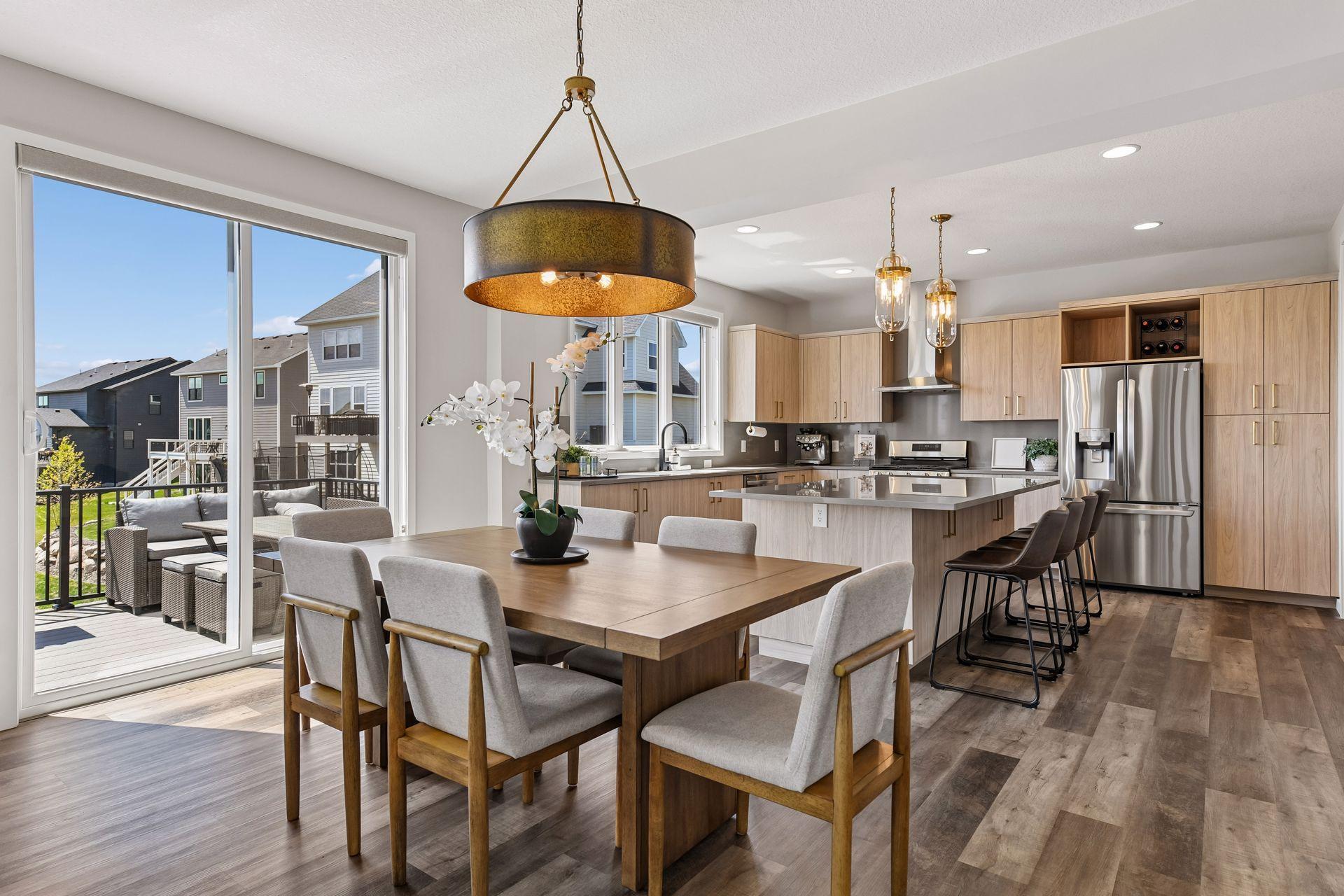 Sunlit informal dining area with statement lighting, seamless kitchen connection, and direct access to the maintenance-free deck.