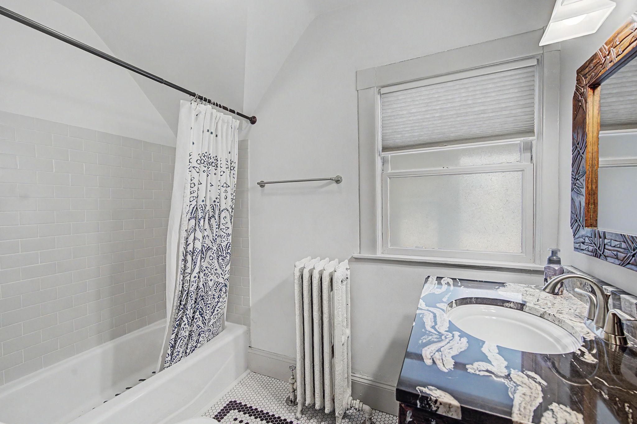 Upper level full bathroom with tiled shower and floors.