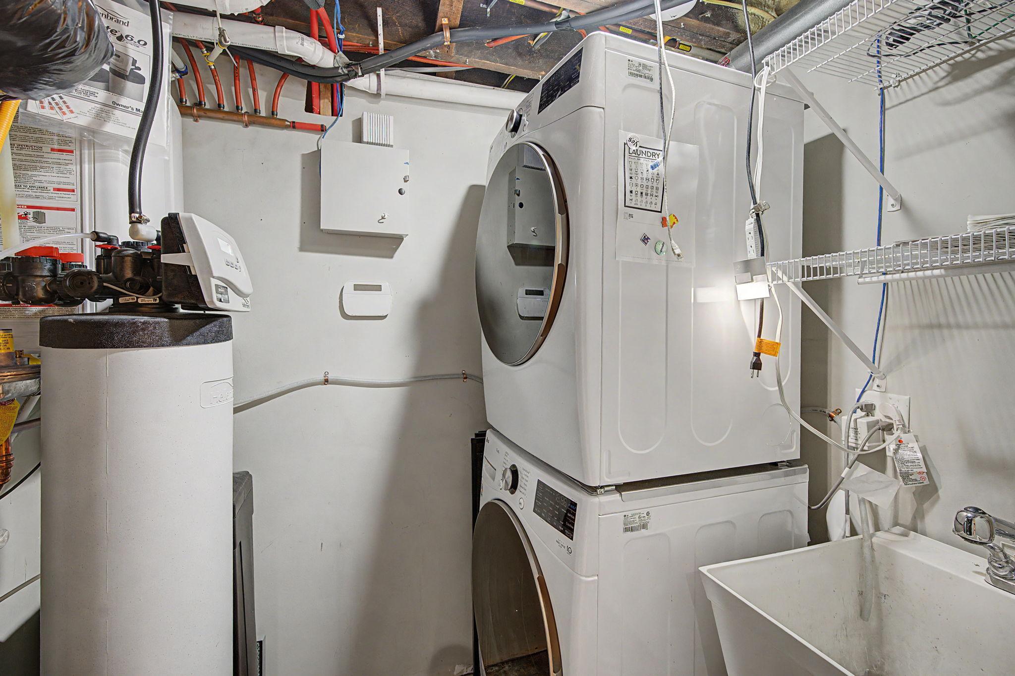 Lower level utility room with washer, dryer, water heater and water softener all replaced in 2024. The utility sink and shelves add extra conveniences.
