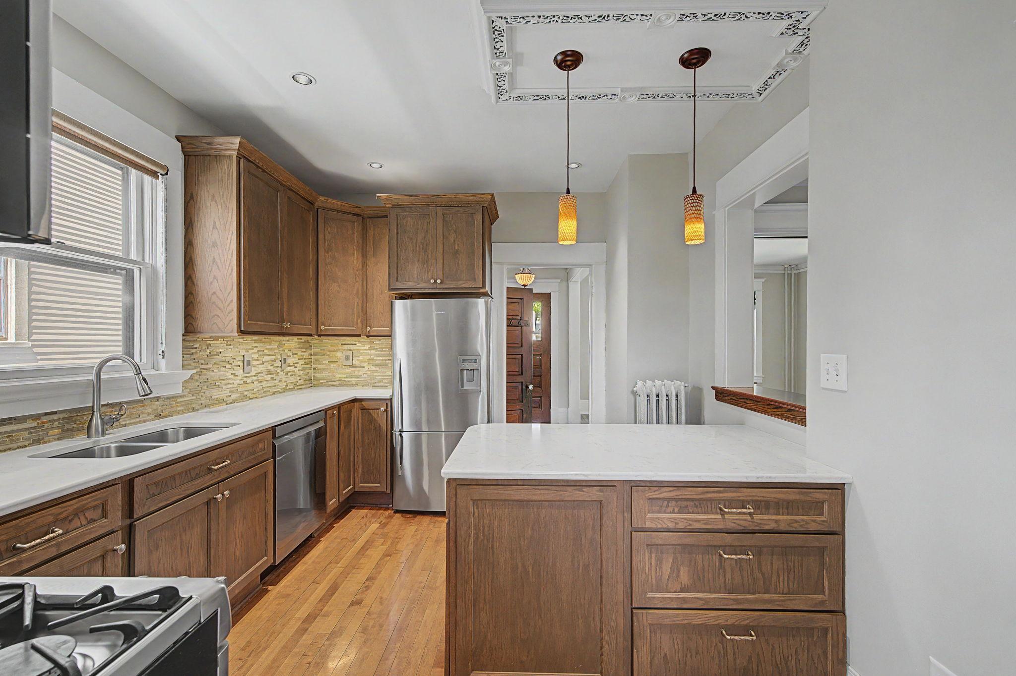The chef-inspired kitchen boasts sleek stone counters, stainless steel appliances, and a designer tiled backsplash.