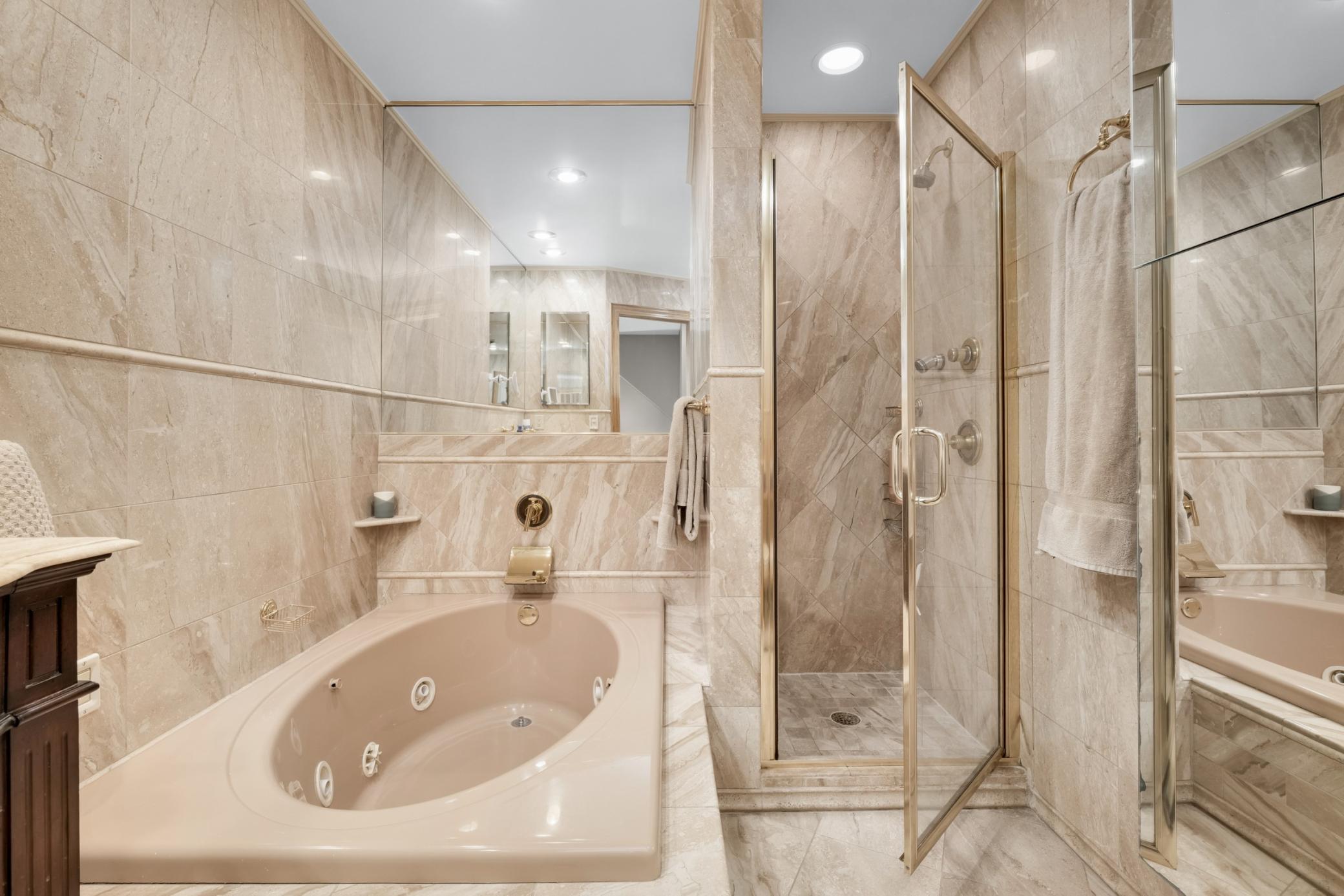 The main bath features marble tile, a jetted tub and walk in shower