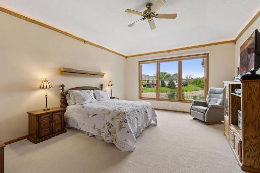 Primary suite with upper cove ceiling lights on remote control, the ceiling has an inlay vault along with views out the back to the lake and pond.