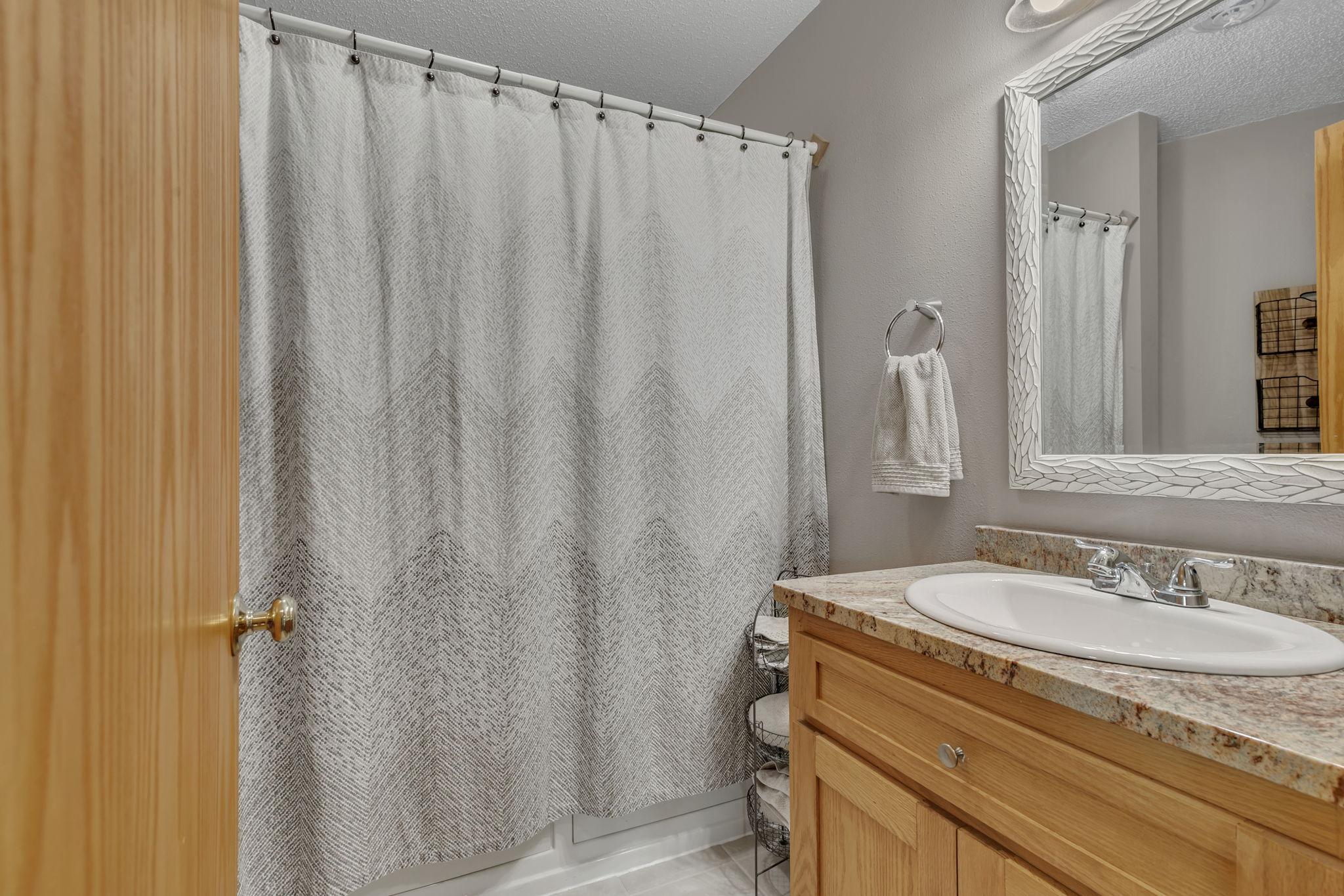 Lower level full bathroom with granite countertops - stool and custom built-in cabintry behind the door.