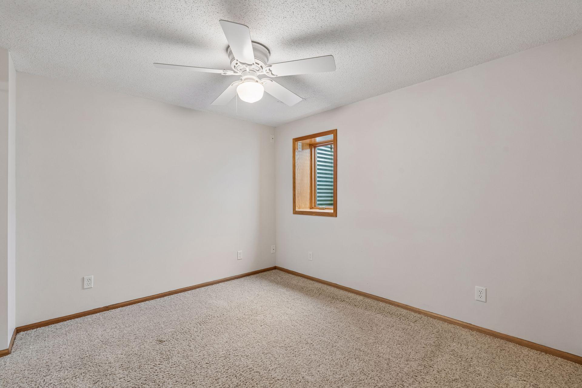 Lower level bedroom with ceiling fan.