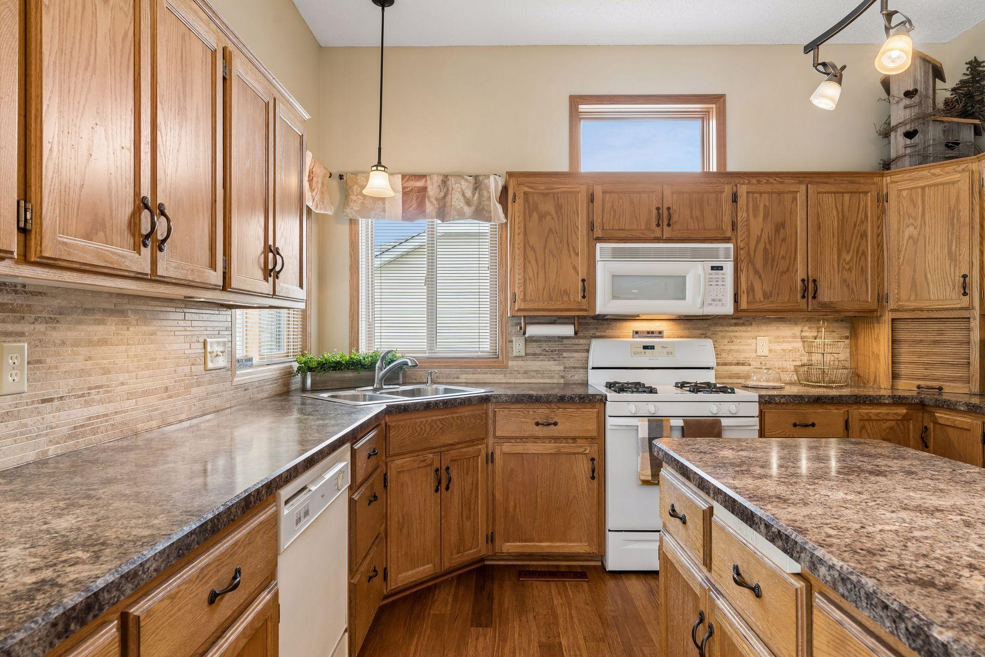 Tile backsplash, abundant counter space, and windows over the sink add both style and functionality to the kitchen.