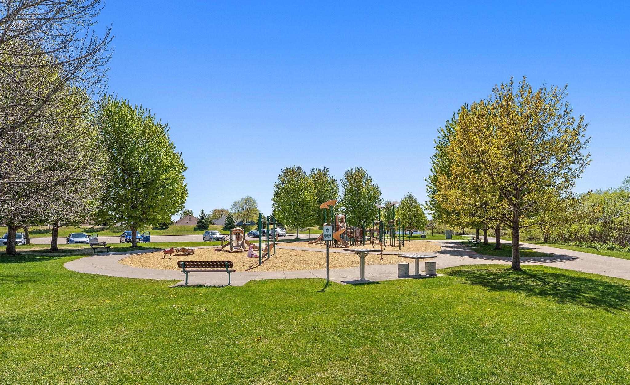 The play area is expansive, featuring a wood-chip base and modern equipment including multiple slides, climbing structures, and swings.