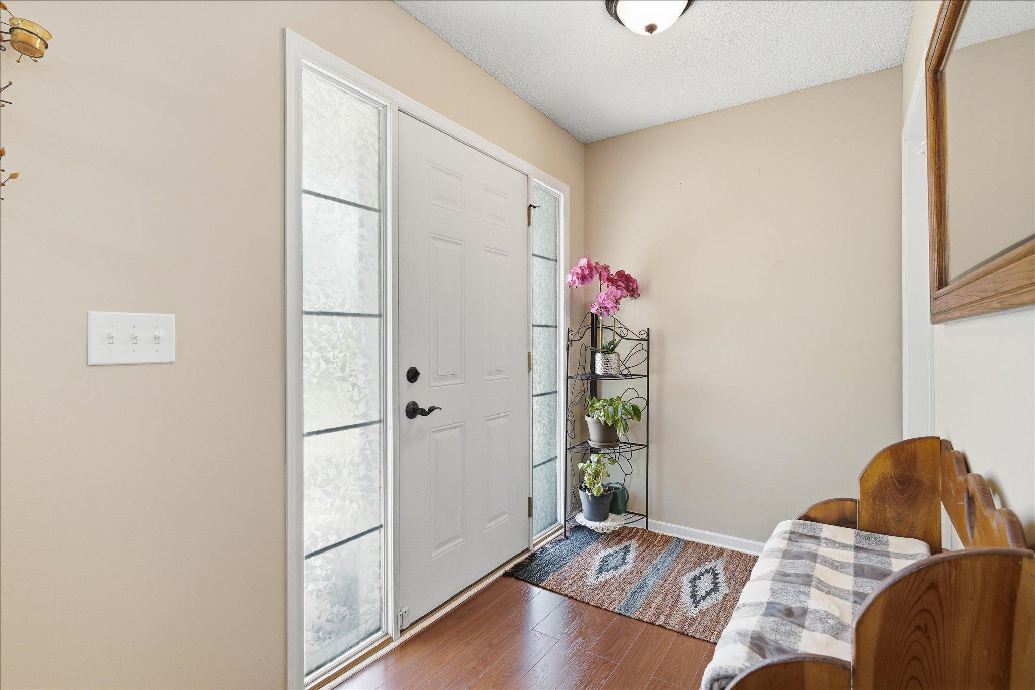Spacious foyer with beautiful wood floors, neutral décor, a large coat closet, and abundant natural light creating a warm welcome.