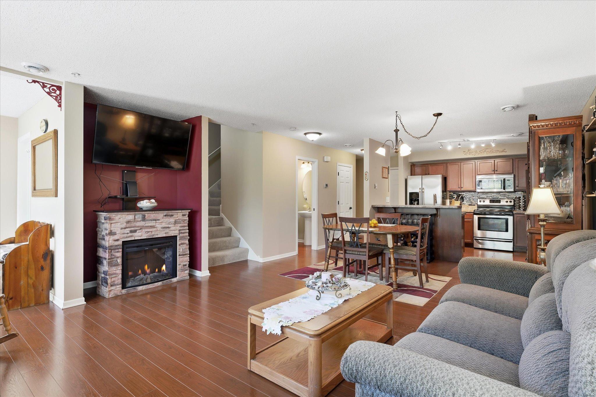 Open-concept layout with cozy electric fireplace, custom stone surround, and seamless flow into the dining and kitchen areas.