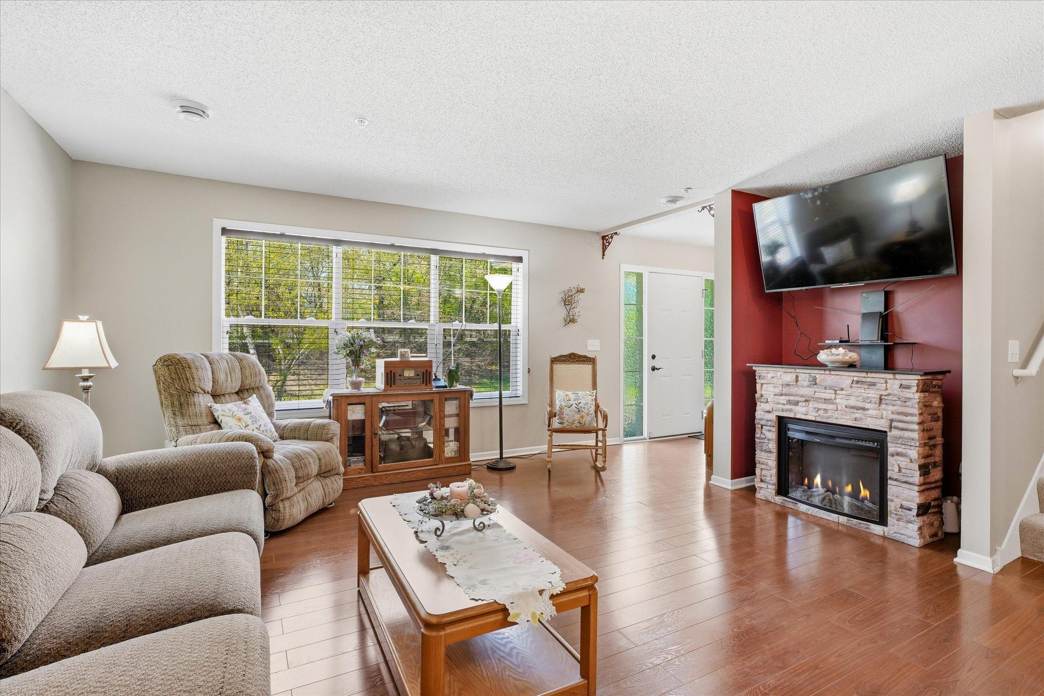 Large living room with expansive windows overlooking peaceful green space and offering plenty of room to relax or entertain.