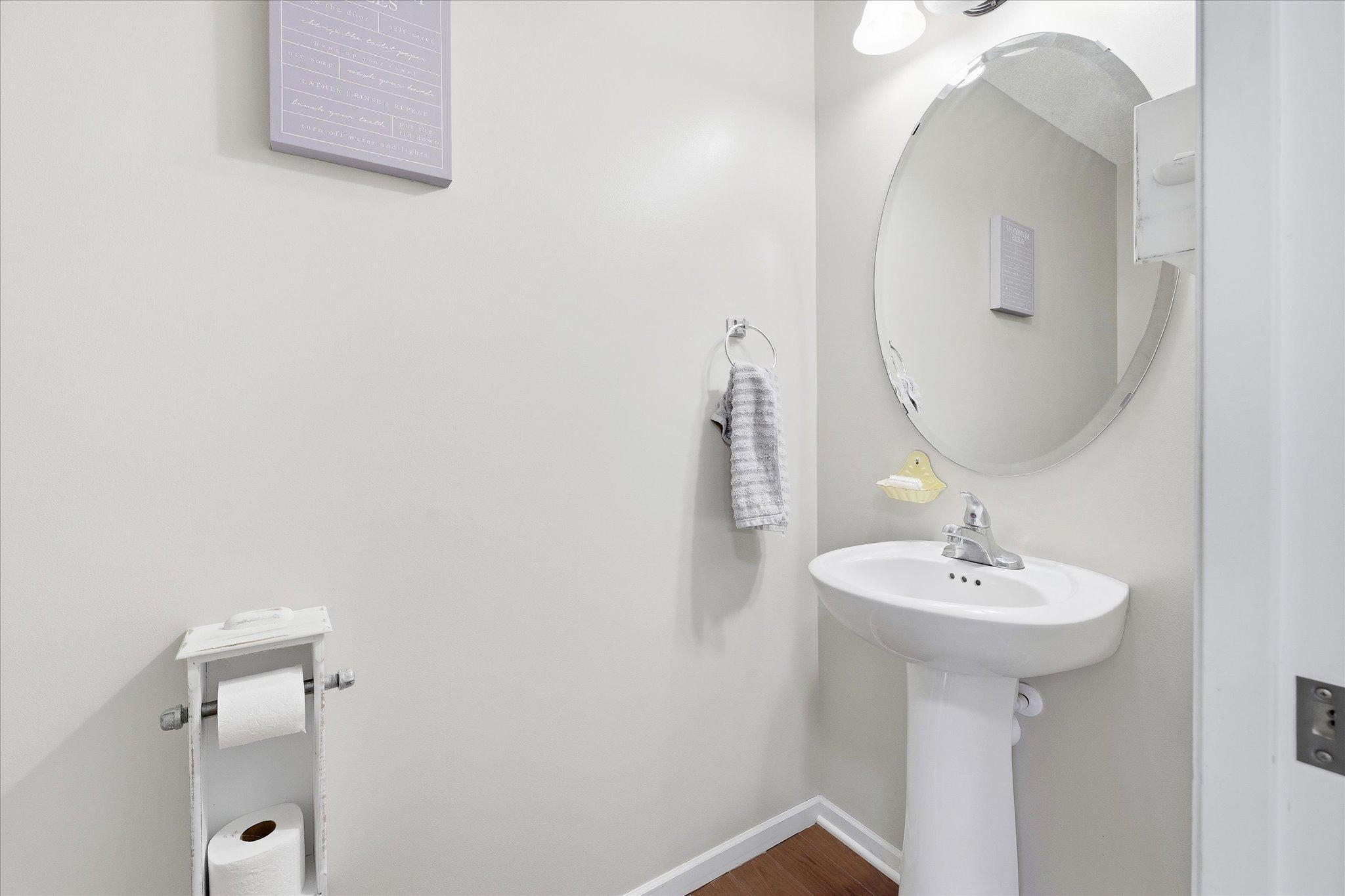 Convenient main-level half bath with neutral finishes and pedestal sink.