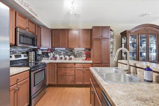 Beautiful kitchen featuring rich cherry cabinetry, stainless steel appliances, a large pantry, stylish tile backsplash, and abundant counter space.