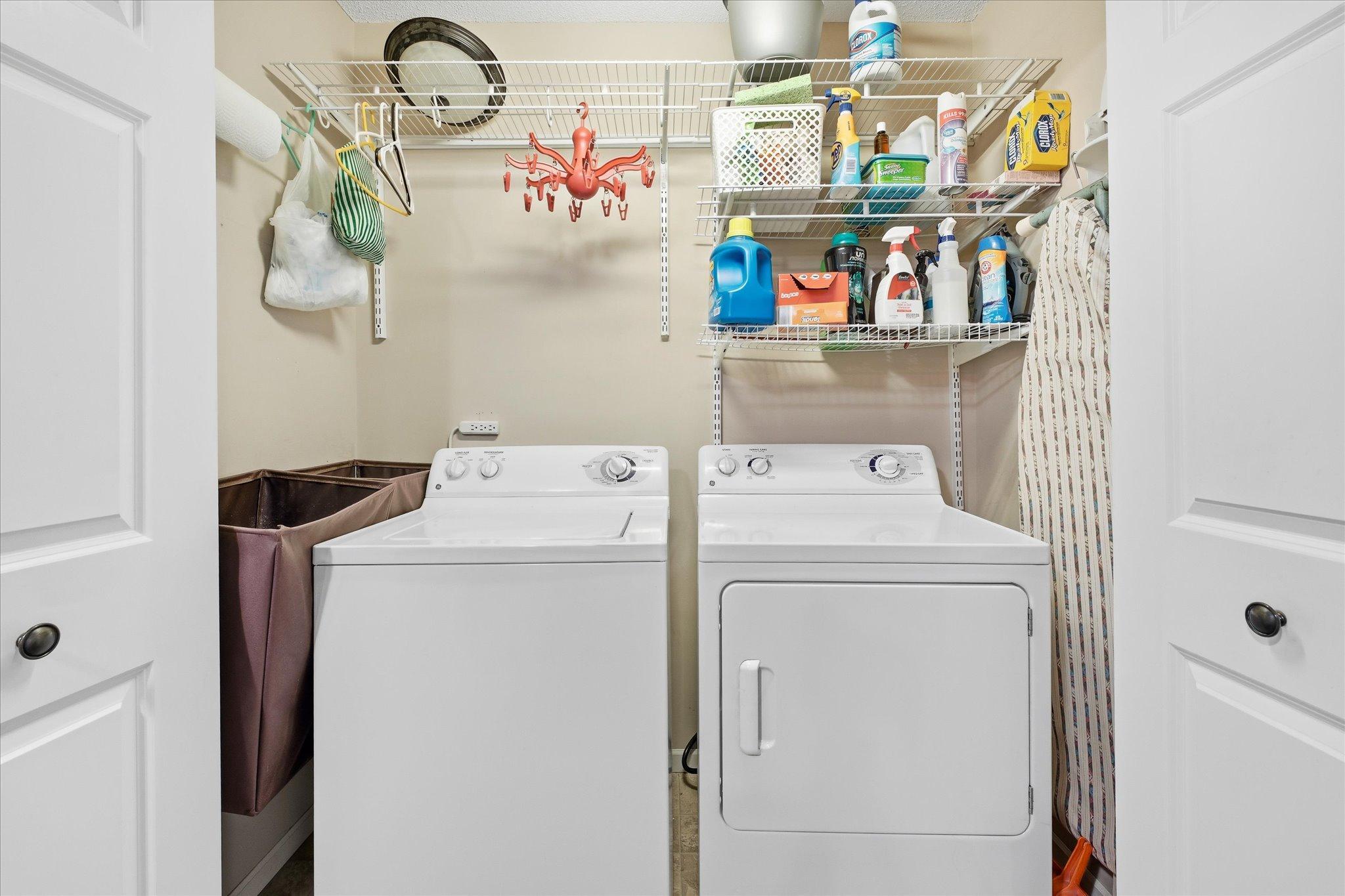 Convenient upper-level laundry area with built-in shelving for extra storage and organization.