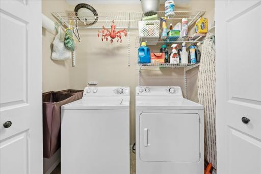 Convenient upper-level laundry area with built-in shelving for extra storage and organization.