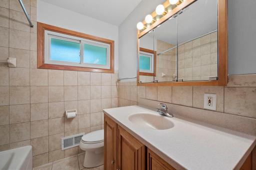 A Nicely appointed full bath on the main floor features ceramic tile and a large vanity